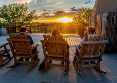 Three people sitting in chairs watching the sunset